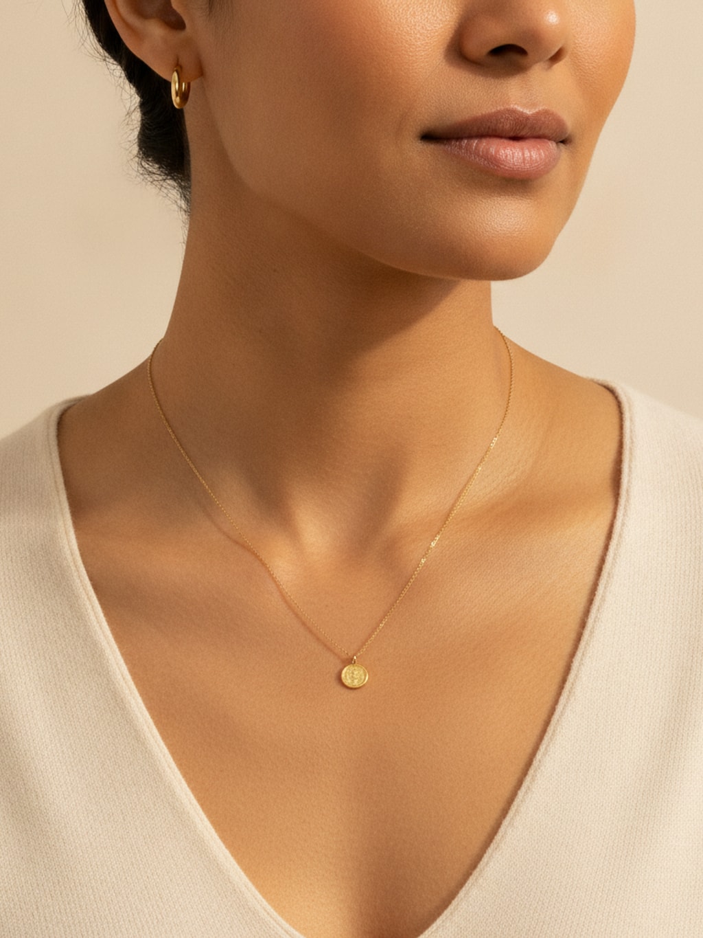 Close-up van hals en sleutelbeen met een fijne gouden schakelketting met hanger en een gouden oorring